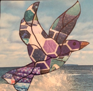 Quilted paper art bird flying above the sea